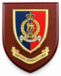 A shield-shaped wooden plaque featuring the Adjutant General's Corps emblem. The plaque has a dark reddish-brown wood grain finish, with a central crest split into blue and red quadrants, topped with a gold crown and laurel wreath, and a gold scroll reading 'ADJUTANT GENERAL'S CORPS' below.
