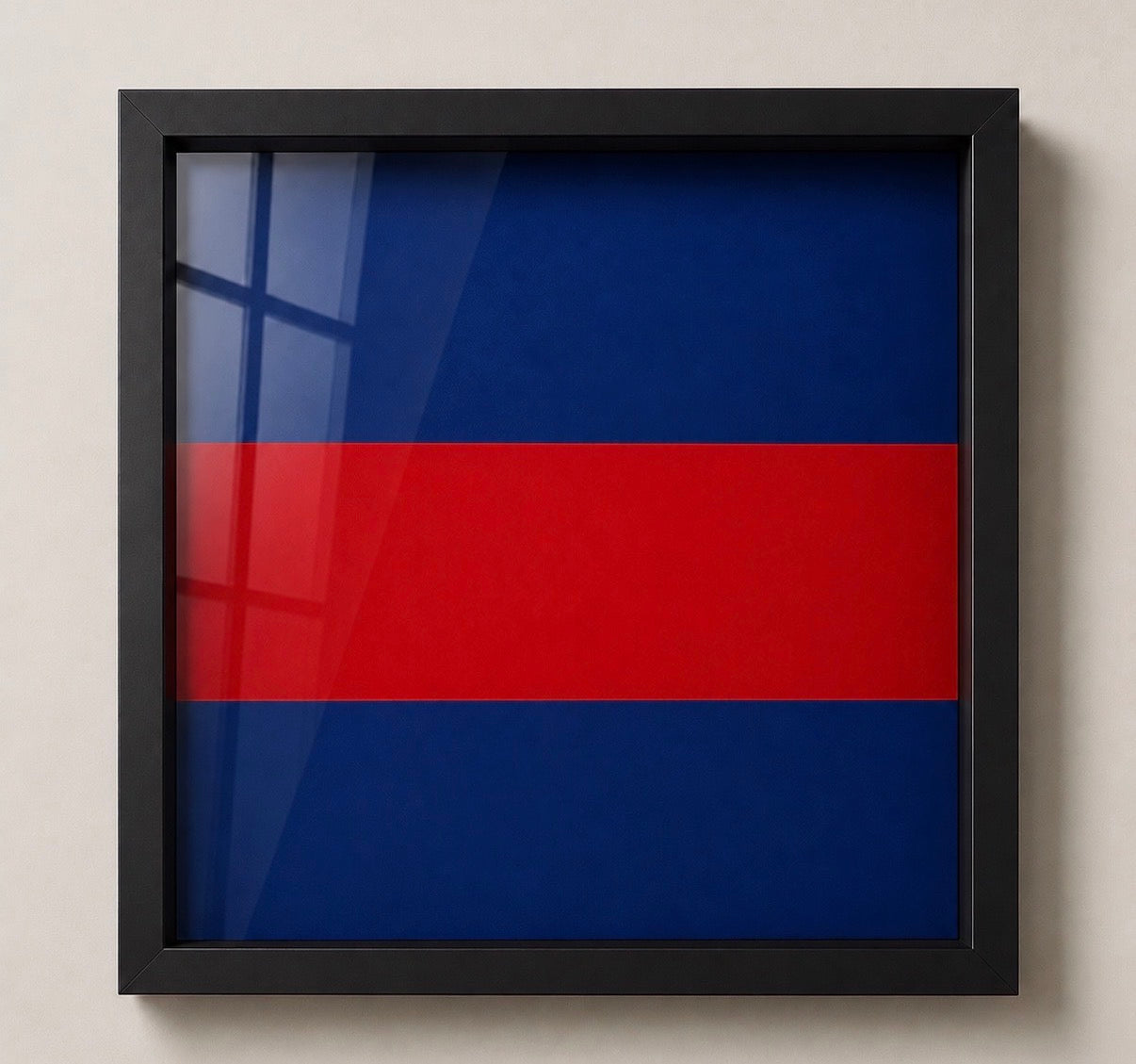 Framed wall art featuring a horizontal tricolor design with blue on top and bottom and red across the center, displayed in a black frame against a light beige wall.
