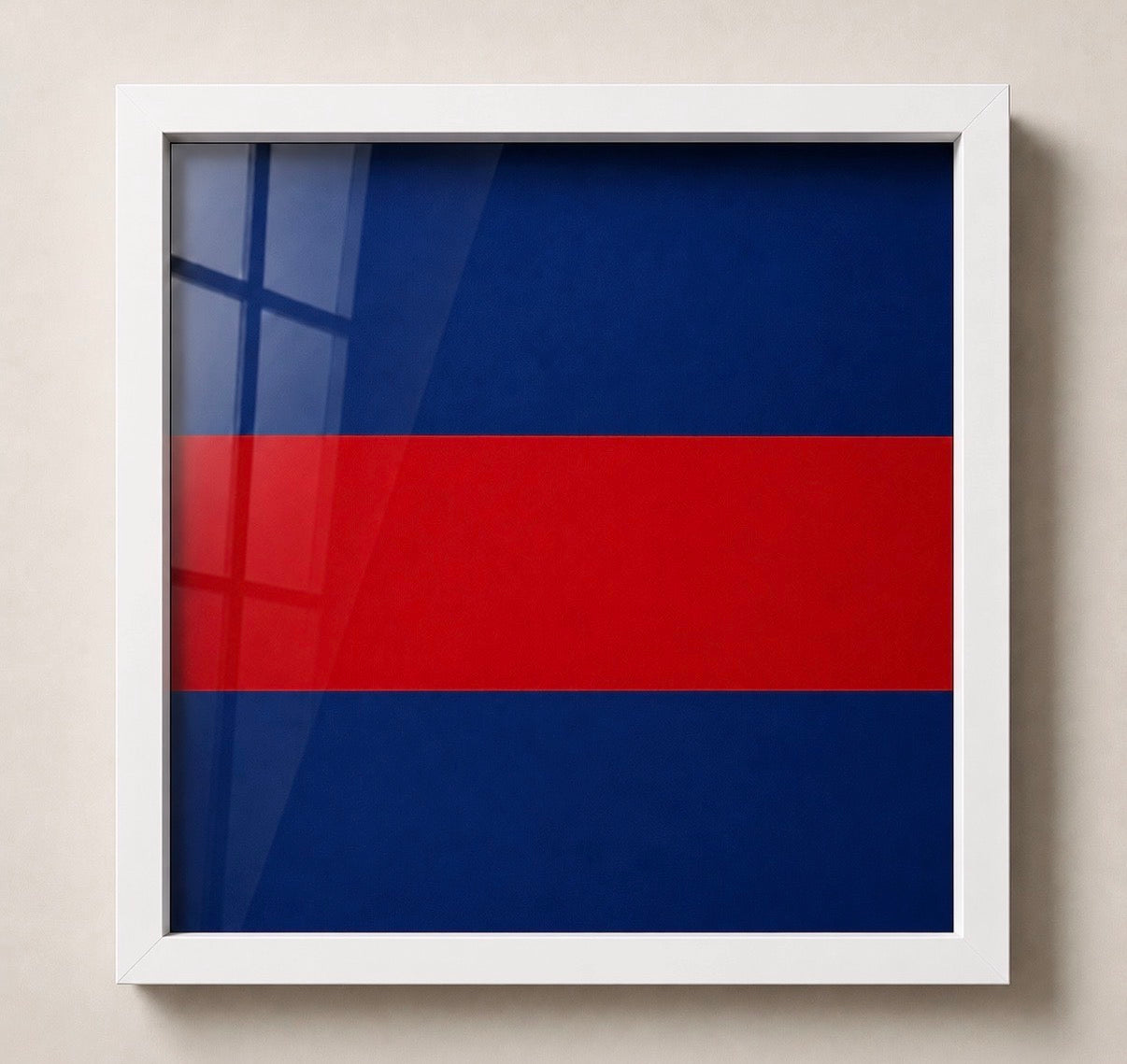 A square framed wall art print featuring a simple horizontal tricolor design with dark blue on the top and bottom sections and a bold red stripe across the middle, mounted against a light beige wall.