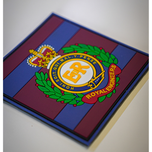 A square glass or acrylic coaster featuring the Royal Engineers crest, set against a background of blue and maroon stripes. The crest is detailed with gold, green, and red elements.