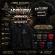 A promotional product graphic for a Royal Artillery 'Artillery Boom' t-shirt. The main product shown is a black crewneck t-shirt with a grey crest graphic on the chest, alongside its back view showing a large distressed 'ARTILLERY BOOM' text print.