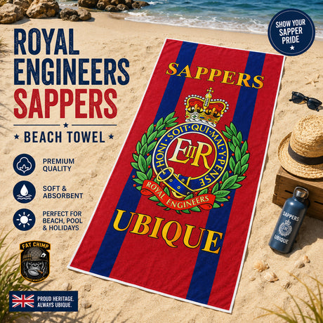 A Royal Engineers Sappers beach towel laid out on a sandy beach next to a straw hat, sunglasses, and a water bottle. The towel features red and navy blue vertical stripes with the Royal Engineers crest in the center and the word 'UBIQUE' printed in yellow at the bottom.