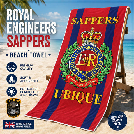 A beach towel featuring the Royal Engineers Sappers UBique club crest, draped over a wooden beach chair on a sandy beach with ocean and palm trees in the background. The towel has red and dark blue vertical stripes with gold lettering and a green wreath.