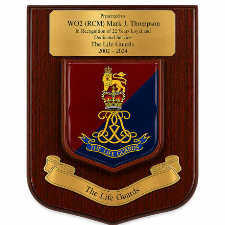 A wooden commemorative plaque with a polished gold-tone top inscription plate and a central shield featuring the Life Guards crest in red and blue with gold detailing, plus a gold scroll reading 'The Life Guards' at the bottom.
