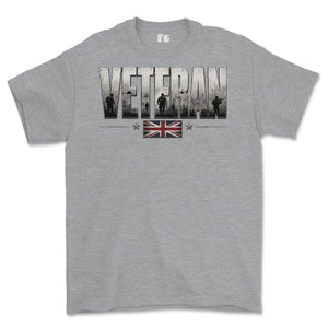 A heather gray short-sleeve crewneck t-shirt featuring a distressed graphic on the chest that reads 'VETERAN' with military silhouettes inside the letters, and a small Union Jack flag graphic below.