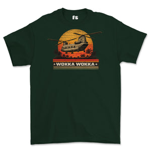 A dark green short-sleeve t-shirt with a retro graphic of a military helicopter flying over a sunset with palm trees and the text 'WOKKA WOKKA'.